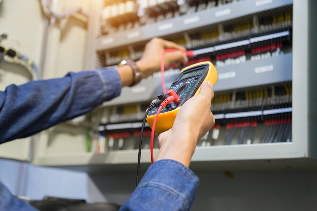 Electrician engineer work  tester measuring  voltage and current of power electric line in electical cabinet control.